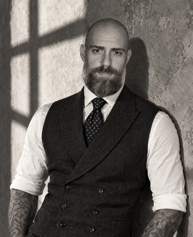 Edoardo Maggiori appoggiato a un muro, in gilet e camicia